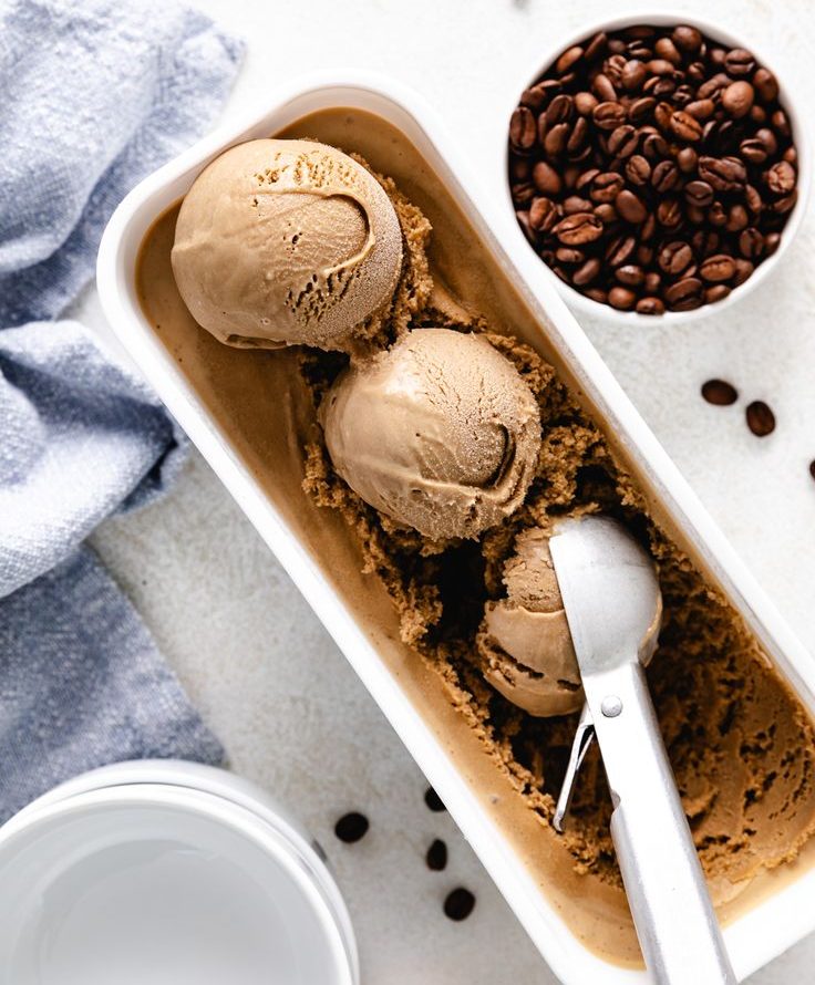 Coffee ice cream in container with scoop and coffee beans